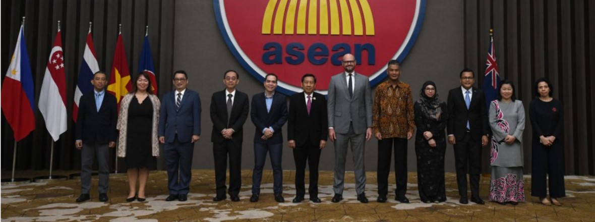 The photo features 12 members of ASEAN standing with flags behind them, and a prominent ASEAN logo in the middle. The background consists of grey walls. Ambassador Bovonethat Douangchak, Permanent Representative of Lao PDR to ASEAN and Country Coordinator for ASEAN-Australia Dialogue Relations, co-chaired the meeting with Ambassador Will Nankervis, Australian Ambassador to ASEAN. 